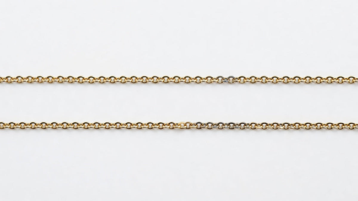 A fine gold-coloured chain with a section where the plating has worn through to the paler metal underneath