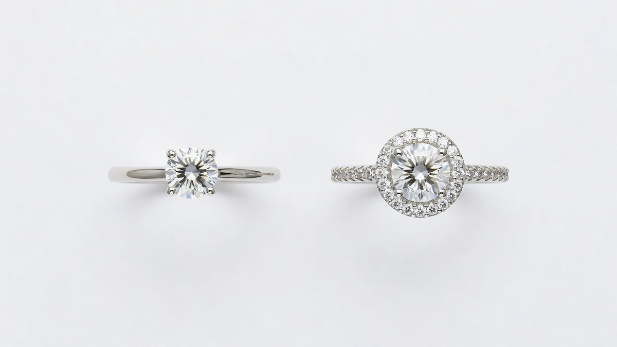 A moissanite solitaire ring and a moissanite halo ring side by side on a white surface for comparison