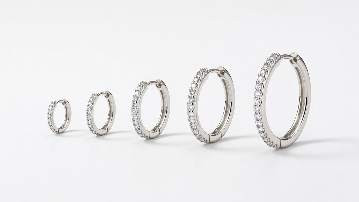 Five moissanite hoop earrings of increasing diameter arranged in a row on a white surface for size comparison