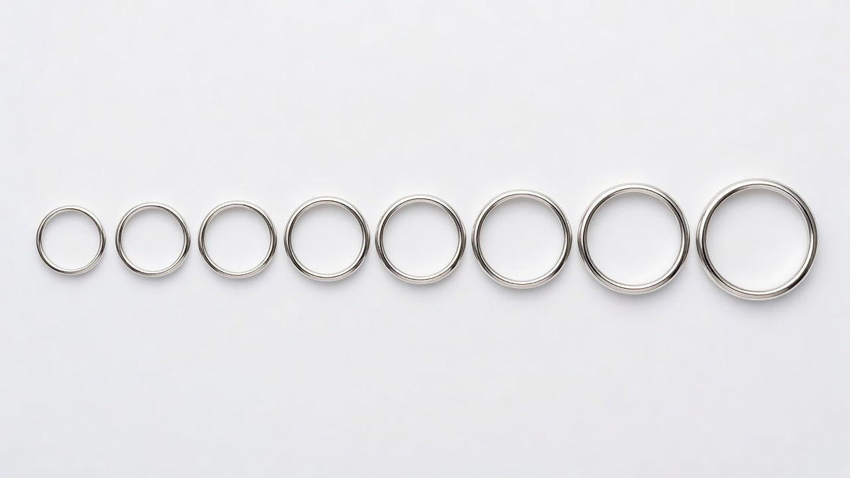 A set of metal ring sizer bands laid out in order on a clean white surface