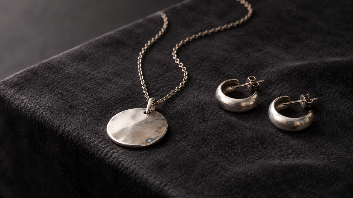 Sterling silver necklace and earrings with light surface tarnish on dark fabric